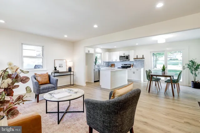 a living room with furniture wooden floor and a kitchen view