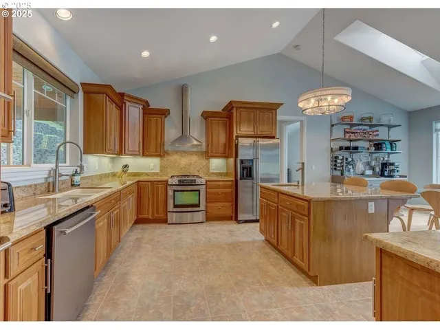 a large kitchen with stainless steel appliances granite countertop a stove a sink dishwasher and a refrigerator
