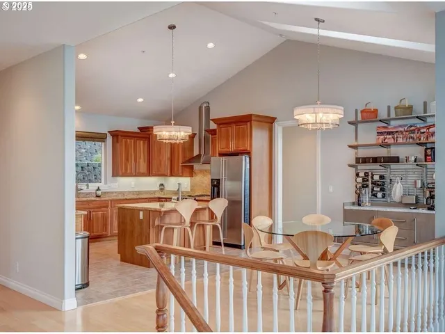 a kitchen with stainless steel appliances kitchen island granite countertop a table chairs and a refrigerator