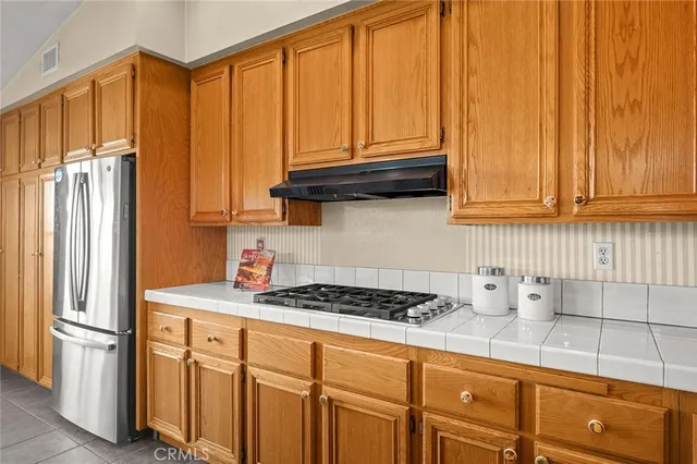 a kitchen with stainless steel appliances granite countertop a refrigerator a sink and wooden cabinets