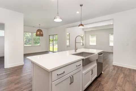 a hall with kitchen island a stove a sink a chimney and wooden floor