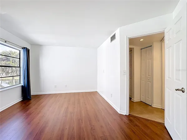 an empty room with wooden floor and windows