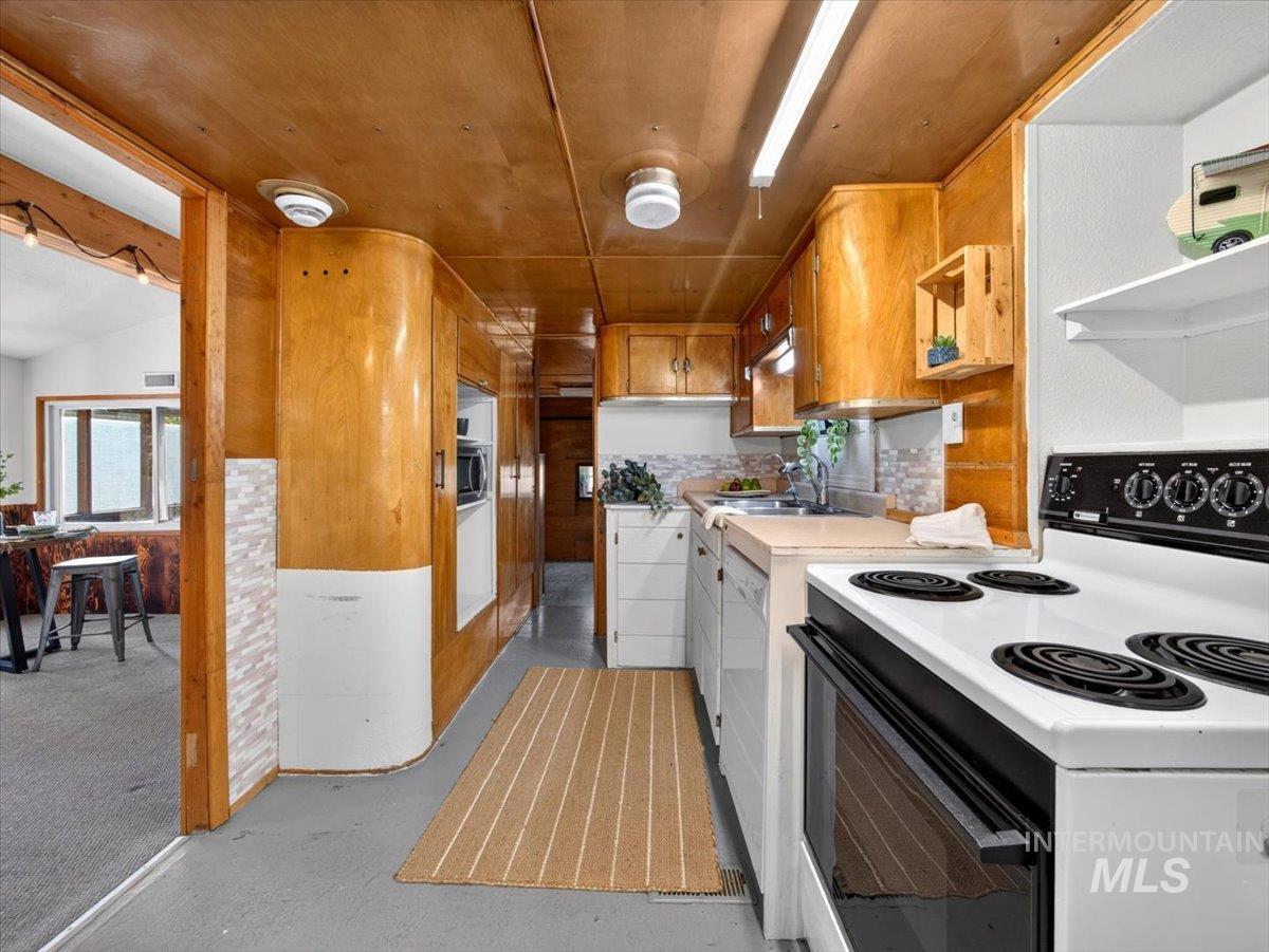 6 Rattlesnake Road Boise City, ID 83716 - Photo 32 of 50 Galley kitchen featuring wood-paneled walls and ceiling, white appliances, and a tiled backsplash