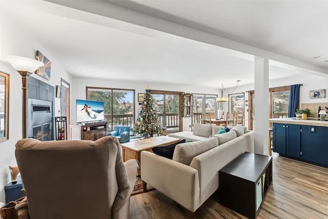 a living room with furniture large windows and wooden floor