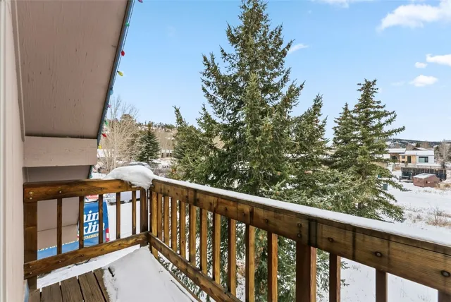 a balcony with wooden floor and trees in the background