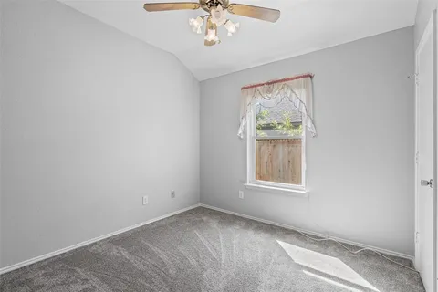 an empty room with windows and chandelier fan