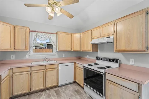 a kitchen with cabinets appliances a sink and a window