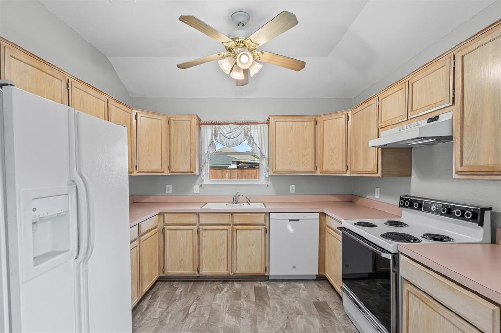 7301 Wagonwheel Road Fort Worth, TX 76133 - Photo 26 of 34 a kitchen with a sink a refrigerator a stove and white cabinets