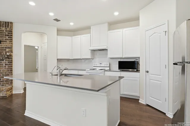 a kitchen with stainless steel appliances granite countertop a refrigerator sink and white cabinets
