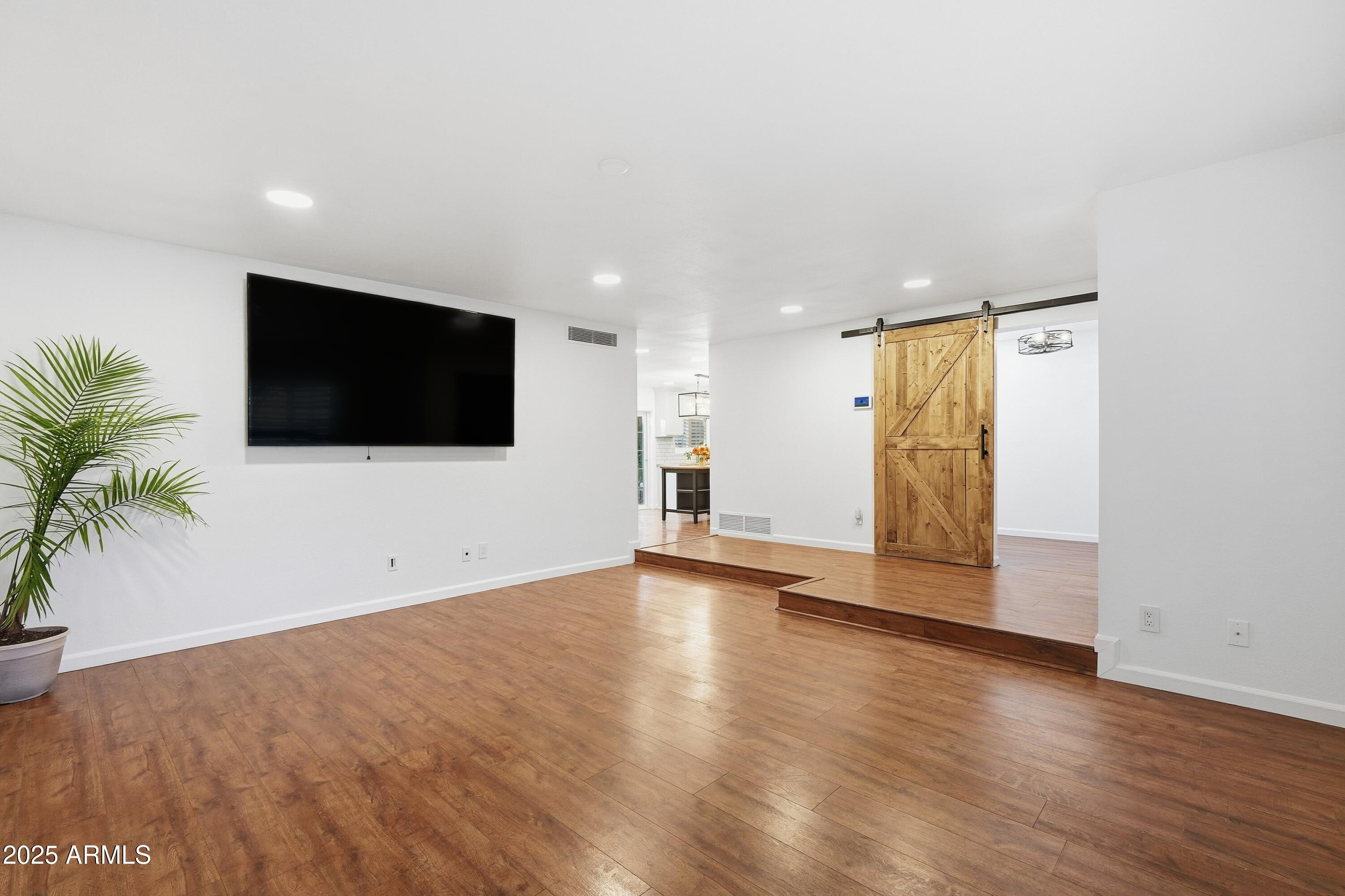 5632 South Jolly Roger Road Tempe, AZ 85283 - Photo 5 of 35 a view of an empty room with wooden floor and a flat screen tv