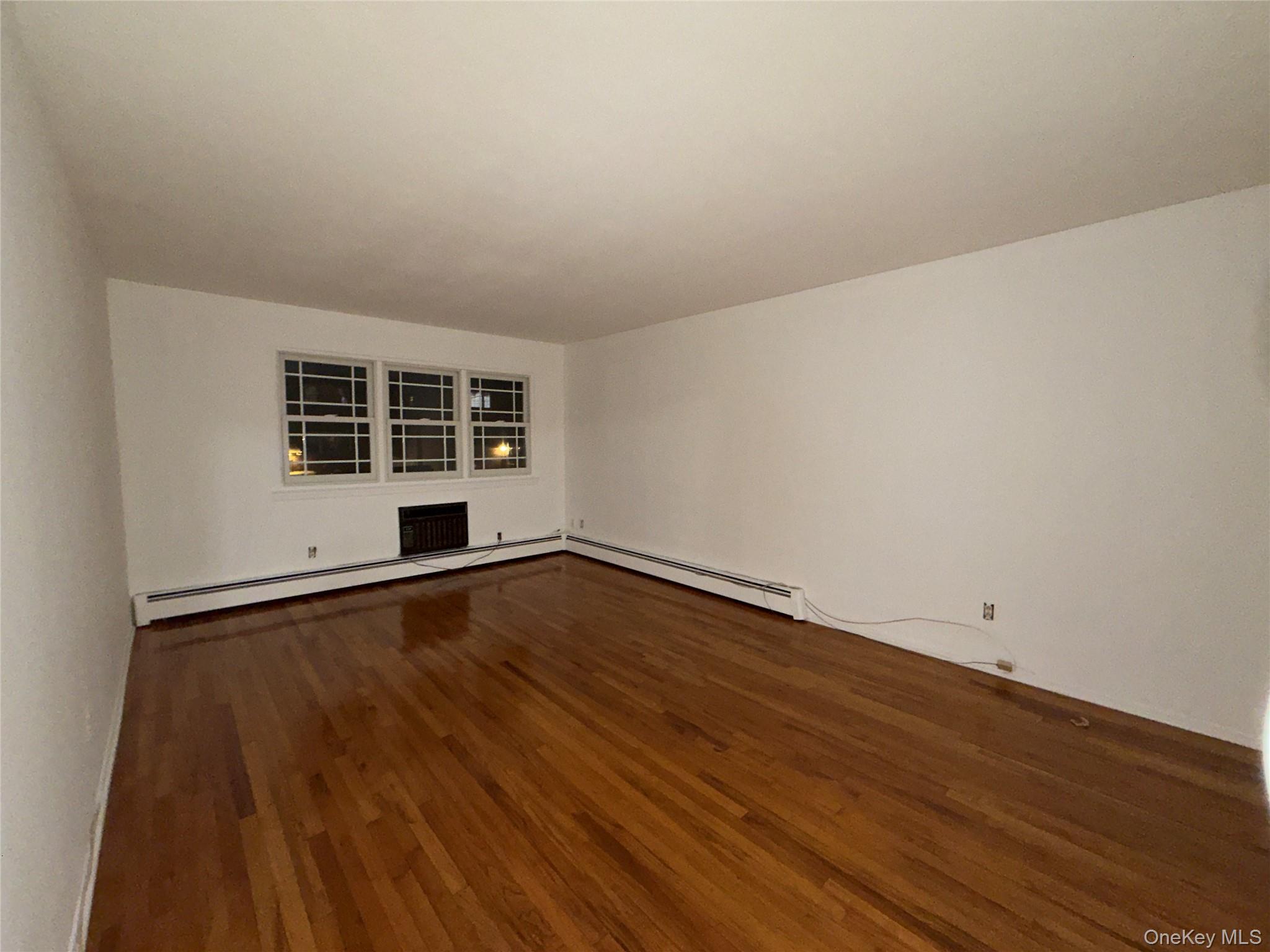 1020 Throggmorton Avenue, Unit 1 Bronx, NY 10465 - Photo 7 of 11 a view of an empty room with wooden floor and windows