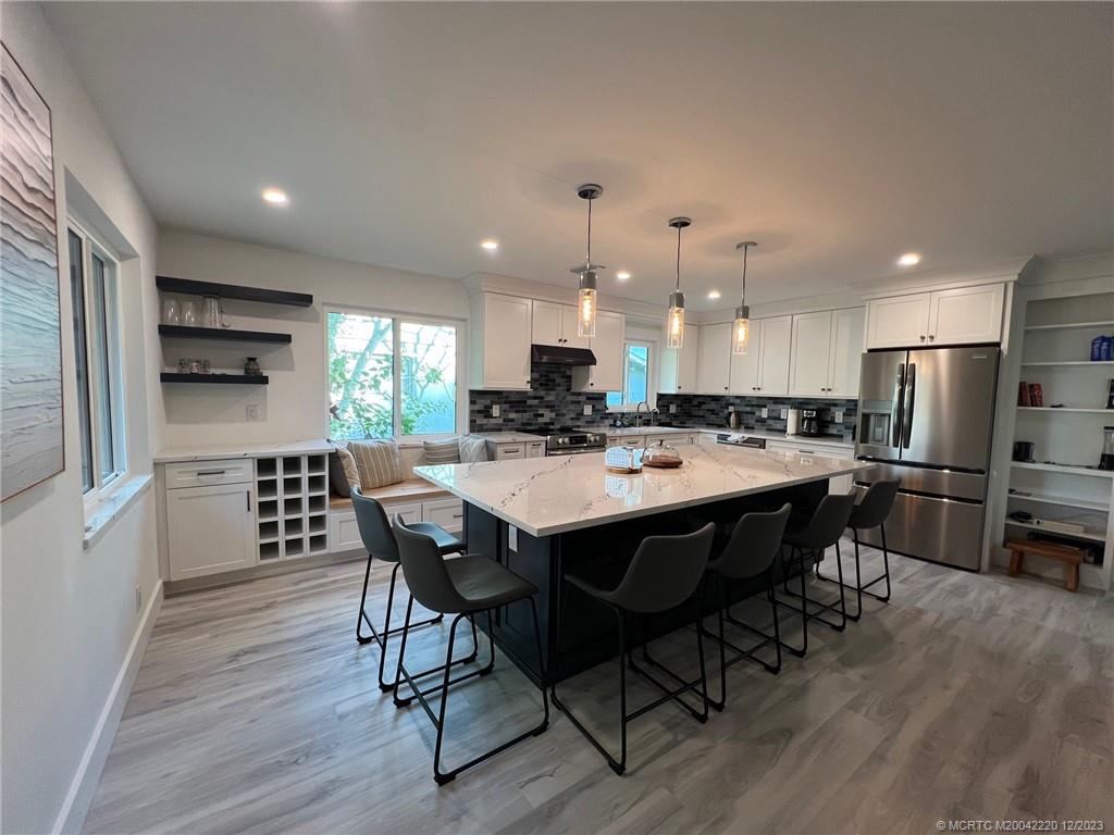 a kitchen with stainless steel appliances kitchen island granite countertop a kitchen island a stove a table and chairs