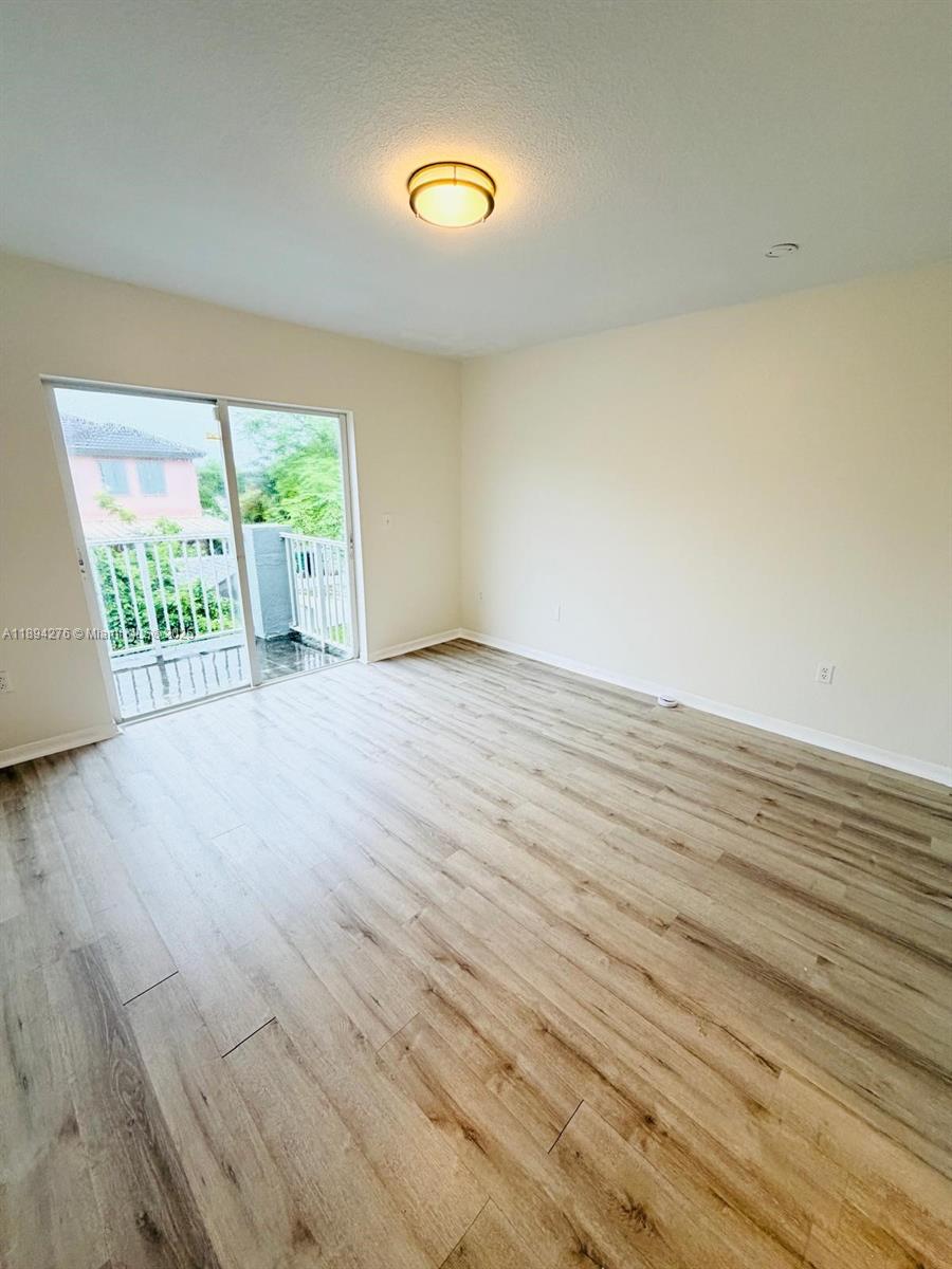 26323 Southwest 135th Place Homestead, FL 33032 - Photo 13 of 23 a view of an empty room with wooden floor and a window