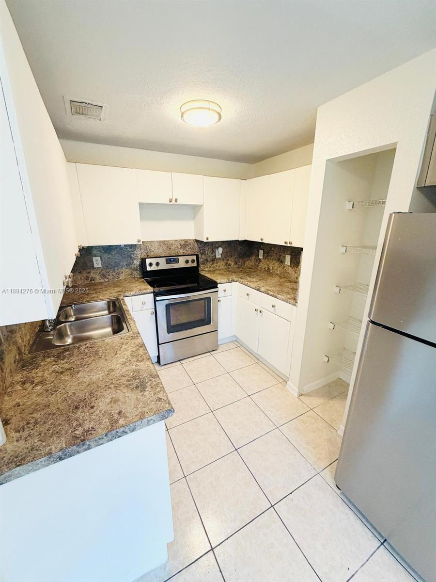 26323 Southwest 135th Place Homestead, FL 33032 - Photo 6 of 23 a kitchen with a stove a refrigerator and a sink
