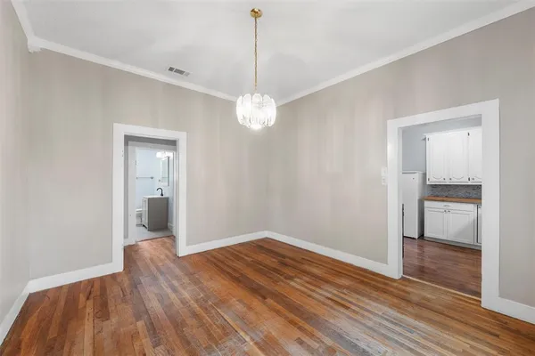 a view of a room with wooden floor a ceiling fan and kitchen space
