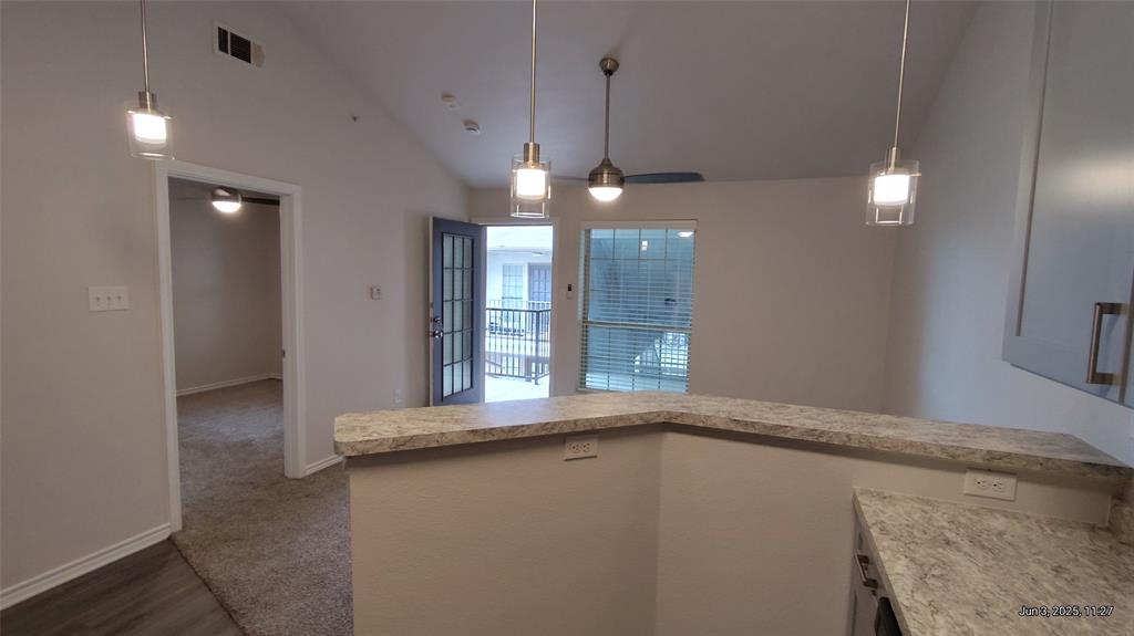 6108 Abrams Road, Unit 522 Dallas, TX 75231 - Photo 4 of 14 Kitchen featuring vaulted ceiling, light countertops, baseboards, hanging light fixtures, and dark wood-type flooring