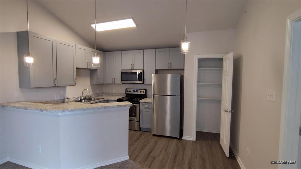 6108 Abrams Road, Unit 522 Dallas, TX 75231 - Photo 5 of 14 Kitchen featuring stainless steel appliances, a sink, wood finished floors, light countertops, and a peninsula