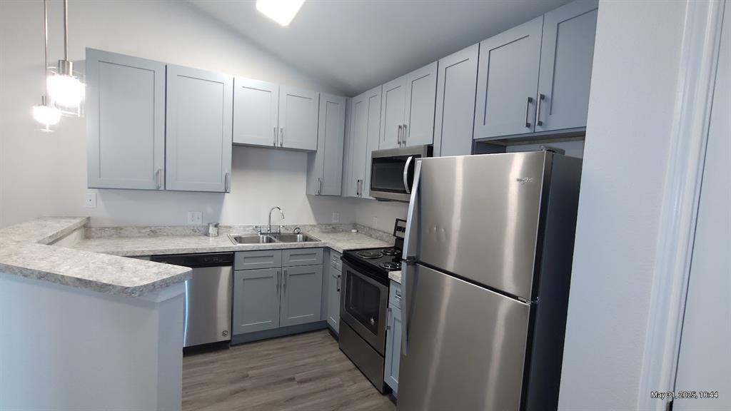 6108 Abrams Road, Unit 522 Dallas, TX 75231 - Photo 7 of 14 Kitchen featuring appliances with stainless steel finishes, a sink, vaulted ceiling, a peninsula, and light countertops