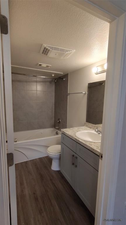 6108 Abrams Road, Unit 522 Dallas, TX 75231 - Photo 8 of 14 Bathroom with a textured ceiling, vanity, wood finished floors, shower / washtub combination, and toilet