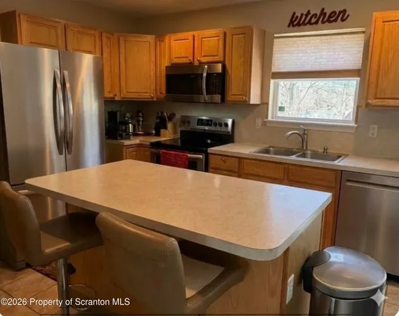 a kitchen with stainless steel appliances a stove a sink a microwave a refrigerator and cabinets