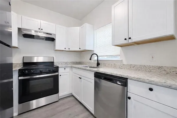 a kitchen with stainless steel appliances granite countertop a sink stove and cabinets