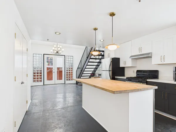 a open kitchen with cabinets a sink and white appliances