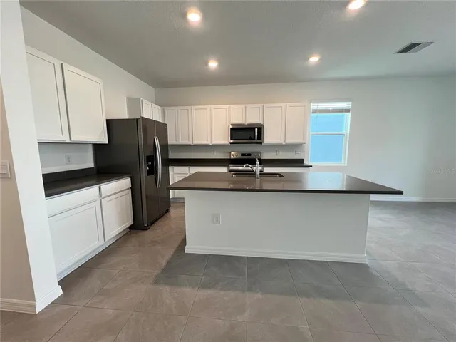 a kitchen with stainless steel appliances granite countertop a stove a sink and a refrigerator