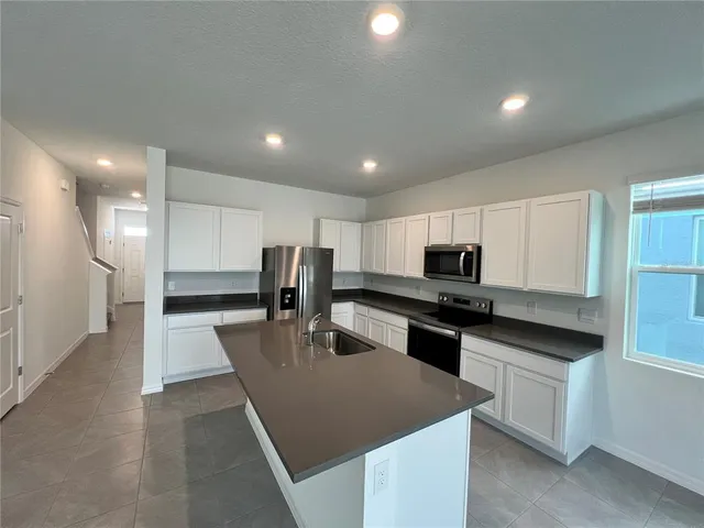 a kitchen with stainless steel appliances granite countertop a sink a stove top oven a counter space and cabinets