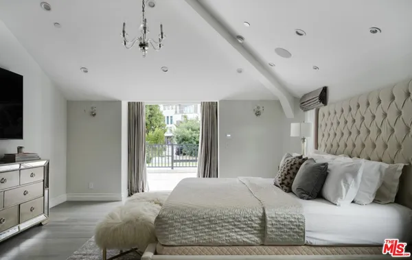 a bedroom with a large bed and a flat tv screen on dresser