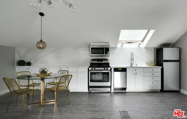 a kitchen with stainless steel appliances a stove a table chairs and a refrigerator