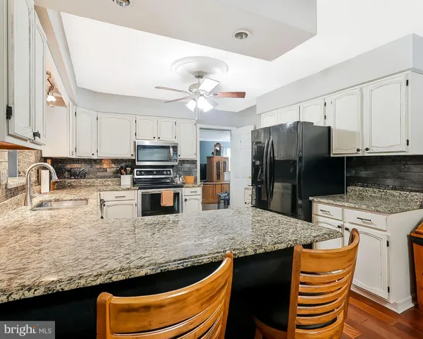 a kitchen with stainless steel appliances granite countertop a sink a stove a refrigerator a washer and island