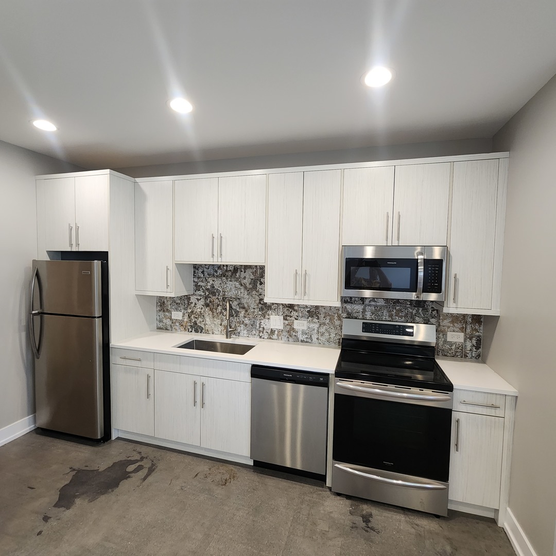 1221 East Marquette Road, Unit G Chicago, IL 60637 - Photo 3 of 11 a kitchen with granite countertop white cabinets and stainless steel appliances
