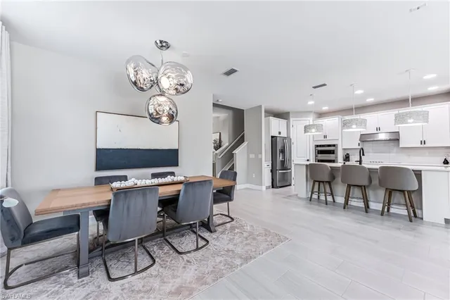 a kitchen with kitchen island a refrigerator a stove a sink a dining table and chairs