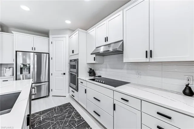 a large kitchen with a counter space a sink appliances and a living room view