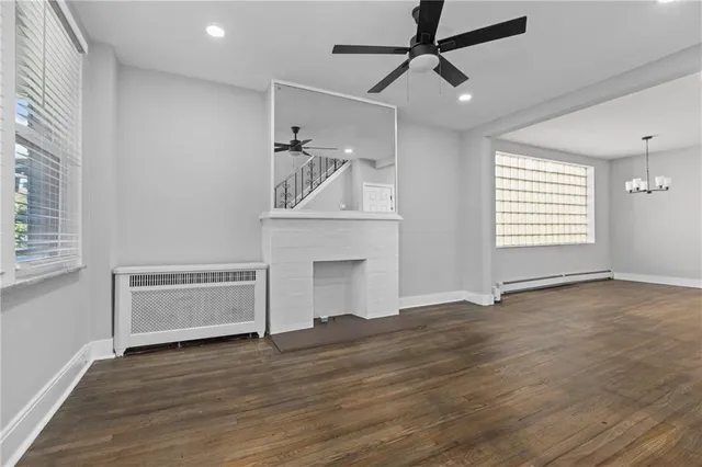 a view of an empty room with wooden floor stairs and a chandelier fan
