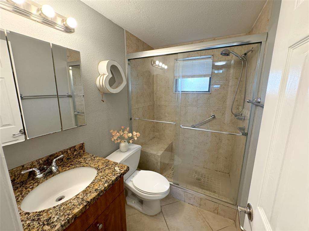1925 Madison Street, Unit 4 Hollywood, FL 33020 - Photo 5 of 11 a bathroom with a granite countertop sink toilet a mirror and shower