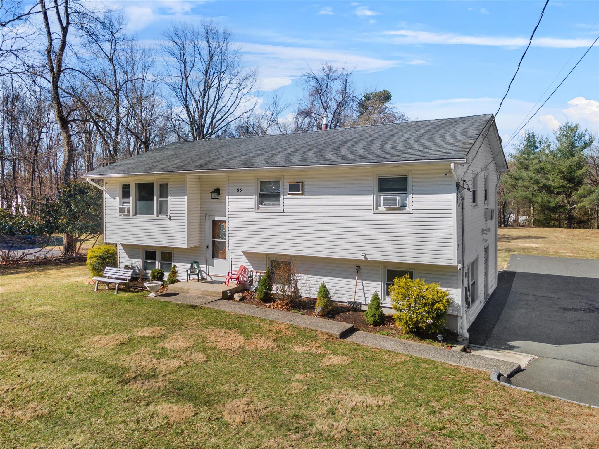 Split foyer home with a patio, a shingled roof, driveway, and a front yard