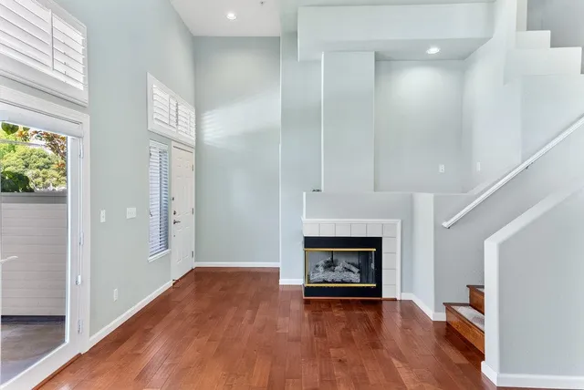 a view of an empty room with wooden floor fireplace and a window
