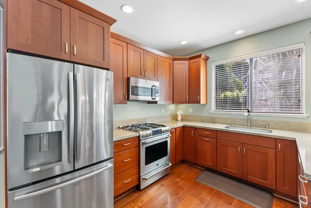 a kitchen with stainless steel appliances granite countertop a refrigerator a sink dishwasher a stove and a microwave oven