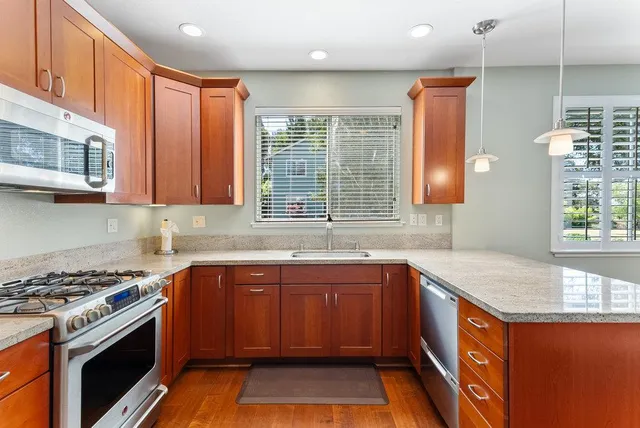 a kitchen with stainless steel appliances granite countertop a sink stove and cabinets