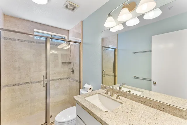 a bathroom with a granite countertop sink mirror and a shower