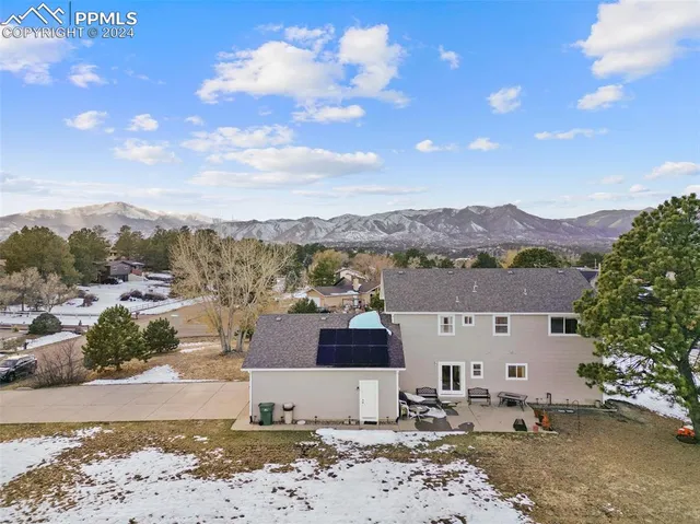 a front view of a house with a yard and mountain view in back