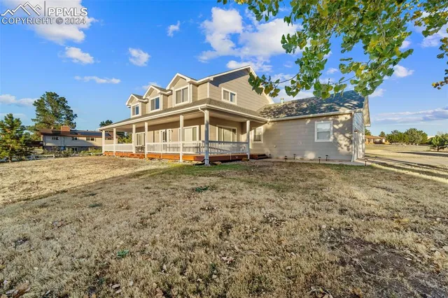 a view of a big house with a big yard and large trees
