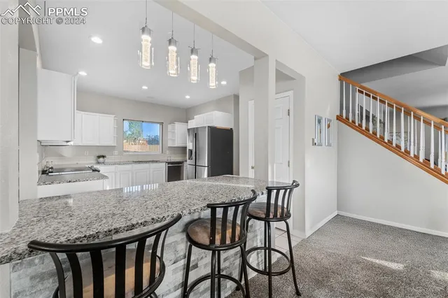 a kitchen with stainless steel appliances kitchen island granite countertop a kitchen island and chairs in it
