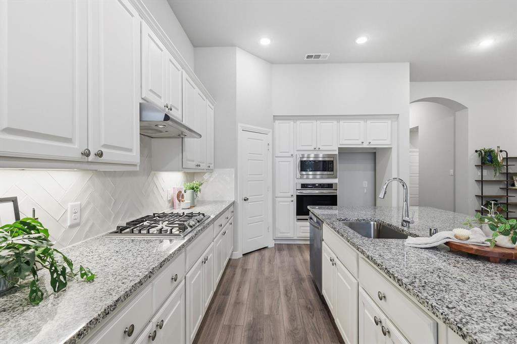 2912 Winding Ridge Court Little Elm, TX 75068 - Photo 15 of 40 Modern Open Concept kitchen with white cabinetry, gas cooktop, ss appliances, farm sink and plenty of storage!