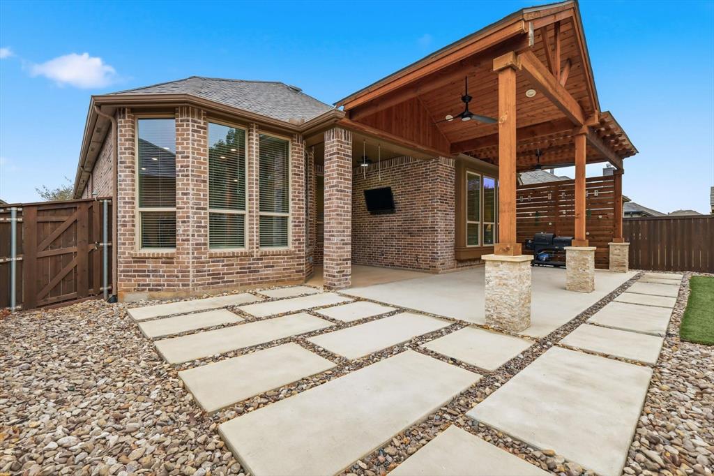 2912 Winding Ridge Court Little Elm, TX 75068 - Photo 4 of 40 Beautiful upgraded back yard with turf, drought tolerant plants, extended patio with a gorgeous outdoor fireplace for cozy gatherings and more!