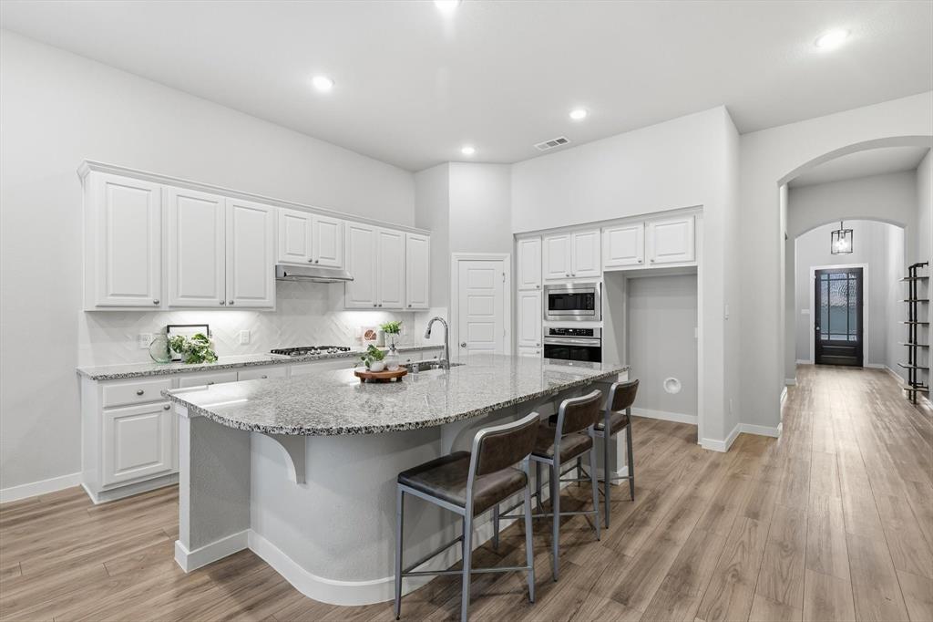 2912 Winding Ridge Court Little Elm, TX 75068 - Photo 9 of 40 Modern Open Concept kitchen with white cabinetry, gas cooktop, ss appliances, farm sink and plenty of storage!