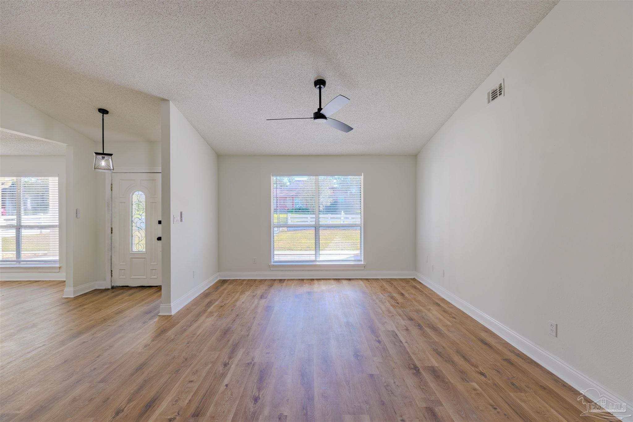 2115 Stallion Road Cantonment, FL 32533 - Photo 12 of 70 a view of an empty room with wooden floor and a window