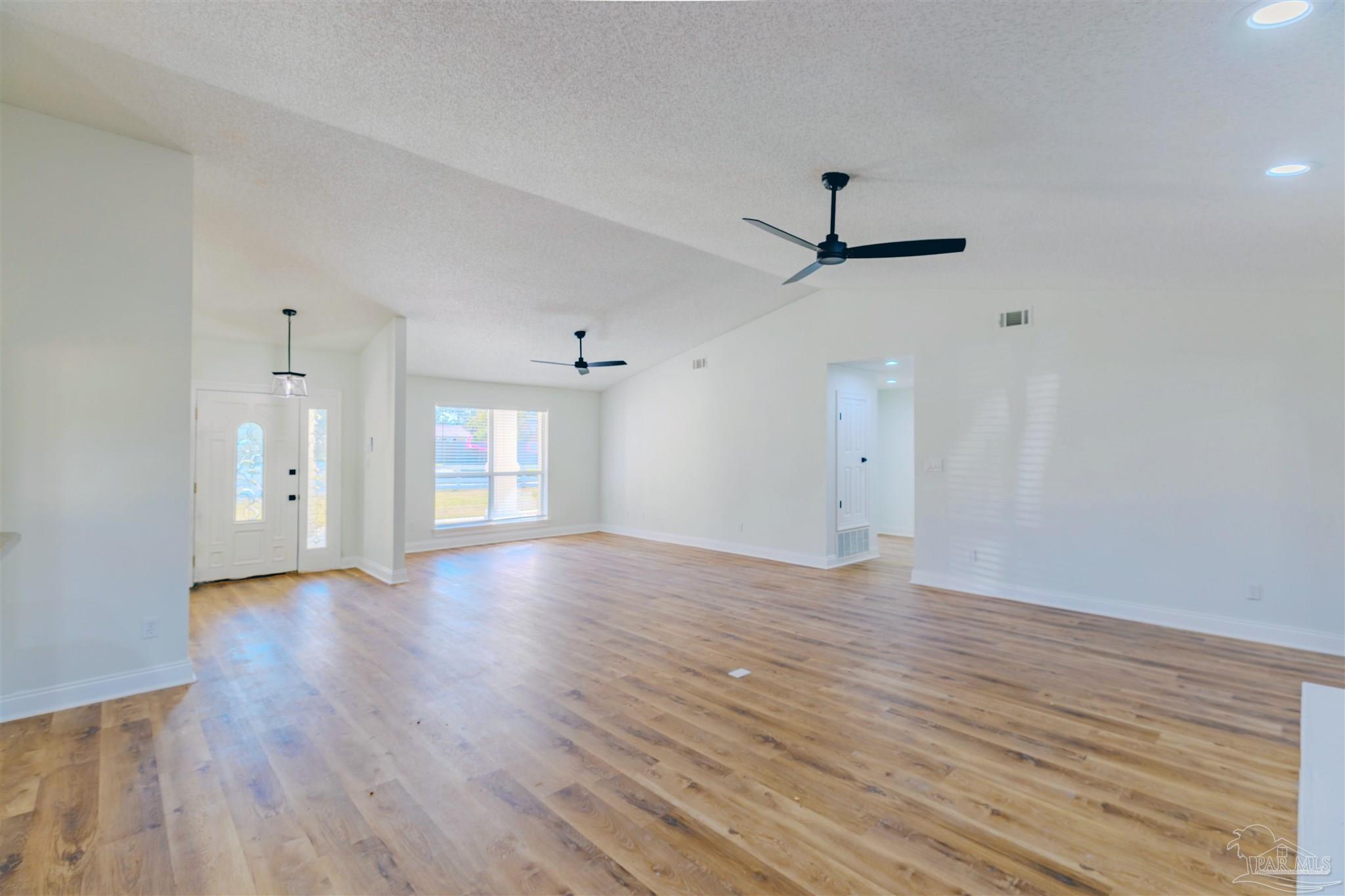2115 Stallion Road Cantonment, FL 32533 - Photo 16 of 70 an empty room with wooden floor ceiling fan and windows