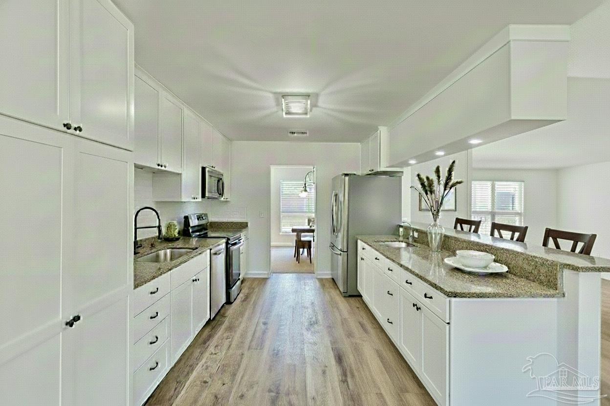 2115 Stallion Road Cantonment, FL 32533 - Photo 21 of 70 a large kitchen with stainless steel appliances granite countertop a lot of counter space and wooden floors